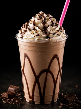 Frappè al cioccolato con panna, scaglie e cannuccia rosa