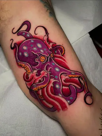 Un polpo viola e rosso a colori sul braccio