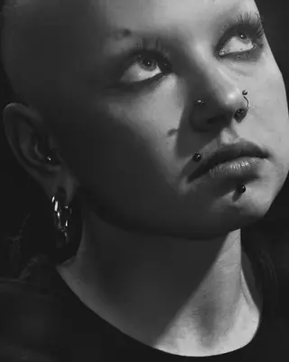 Una ragazza con piercing al naso, al labbro e alle orecchie