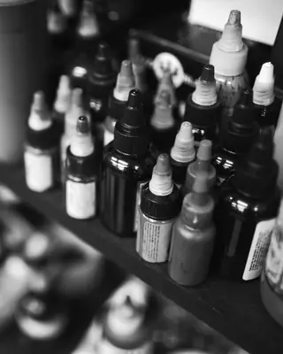 Flaconi di inchiostro per tatuaggi allineati su uno scaffale