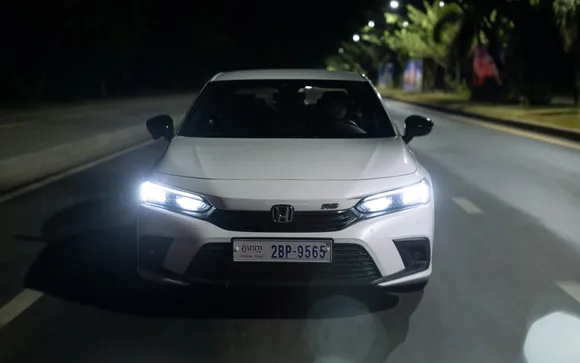 Una Honda Civic bianca di notte, con i fari accesi