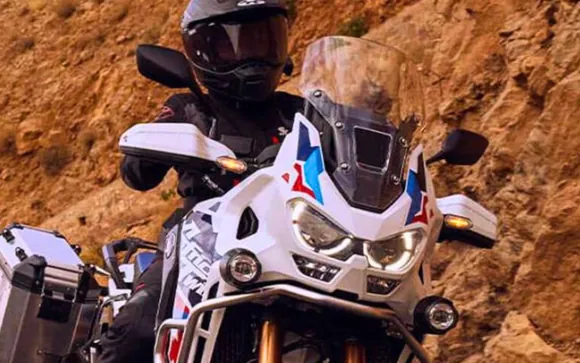 Un motociclista su una Honda Africa Twin bianca, rossa e blu, fra le rocce