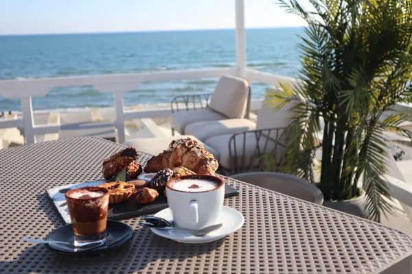 Cappuccino e cornetti su un tavolo in terrazza, davanti al mare
