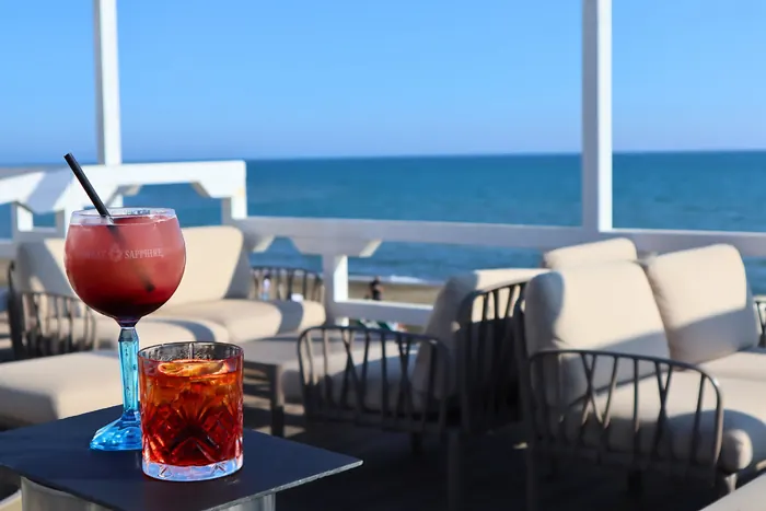 Due cocktail su un tavolino della terrazza, con i divanetti e il mare alle spalle