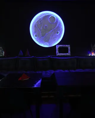 La luna luminosa sulla parete, sopra i divanetti in luce blu
