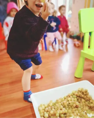 Un bambino ride in aula accanto a una vaschetta piena di ceci