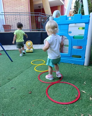 Due bambini giocano in giardino, saltando nei cerchi colorati