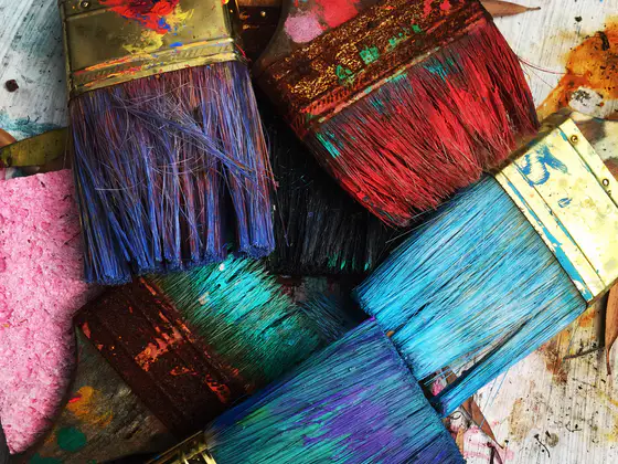 Pennelli sporchi di colore, blu, rosso, rosa e turchese, uno accanto all’altro