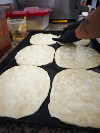 Dischi di pasta per la pizza stesi a mano sulla teglia