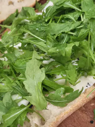 Pizza bianca coperta di rucola fresca