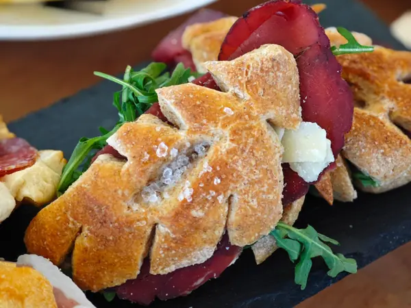 Spighe di pane ripiene di bresaola e rucola, su un’ardesia