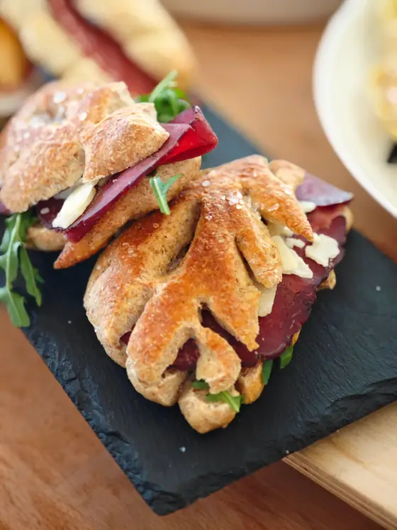 Una spiga di pane farcita con bresaola e rucola, su un’ardesia