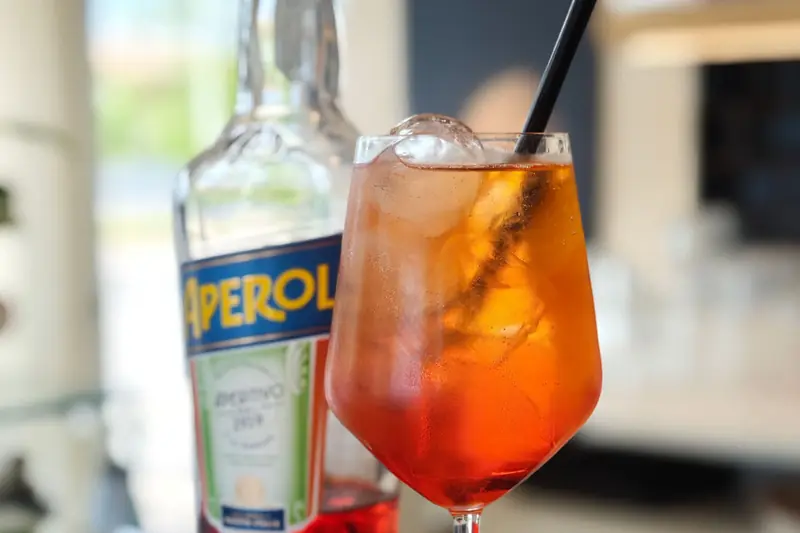 Uno spritz con la fetta d’arancia, accanto alla bottiglia