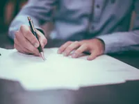 Una mano che firma un foglio con la penna