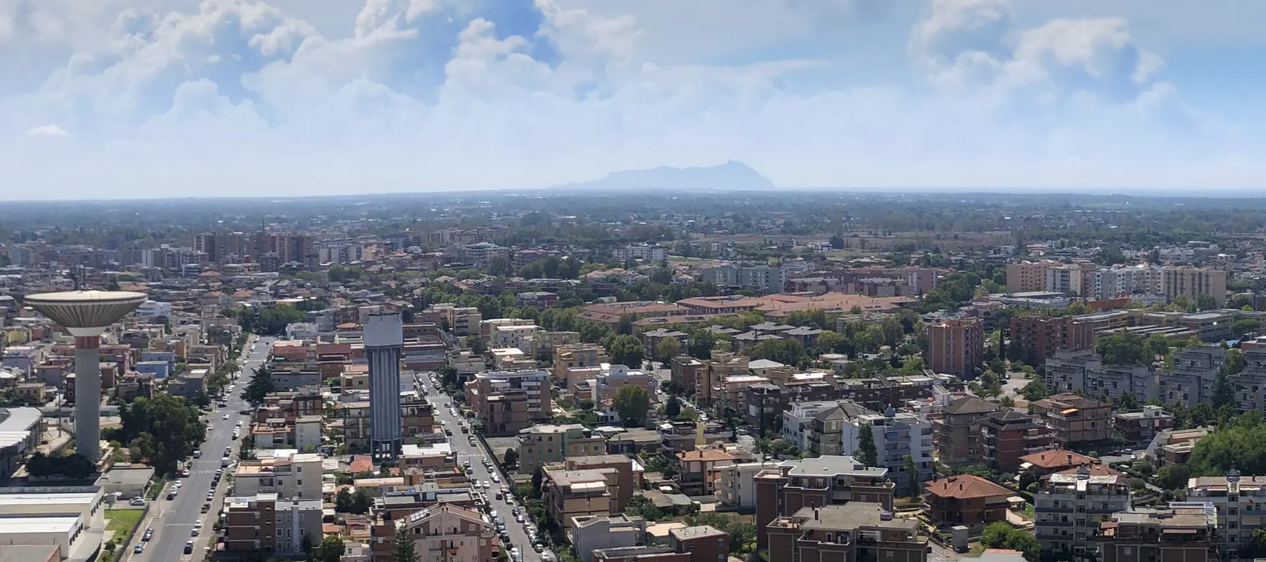 Latina vista dall'alto, con i serbatoi dell'acqua, i palazzi e il Circeo sull'orizzonte