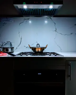 Il piano cottura di una cucina, con la cappa accesa sul marmo