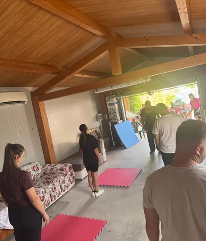 La sala con i tappetini rossi e il portone aperto sul giardino, con gli allievi che entrano