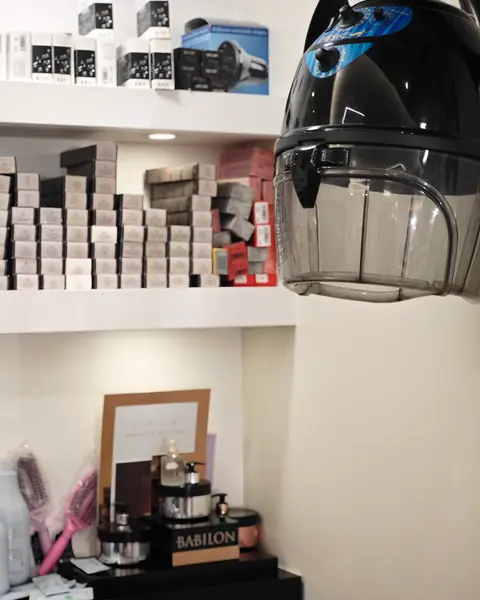 Il casco asciugacapelli davanti agli scaffali delle tinte