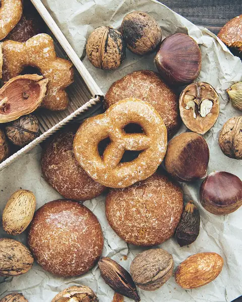 Biscotti, ciambelline e frutta secca sparsi sulla carta del forno