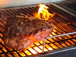Una bistecca sulla griglia, sopra la brace accesa