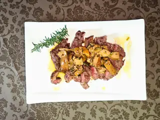 Tagliata con funghi e rosmarino su un piatto bianco