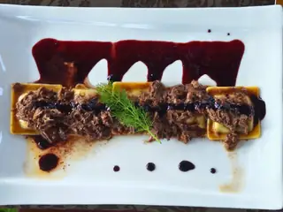 Carne sfilacciata con una riduzione di vino rosso, su un piatto bianco