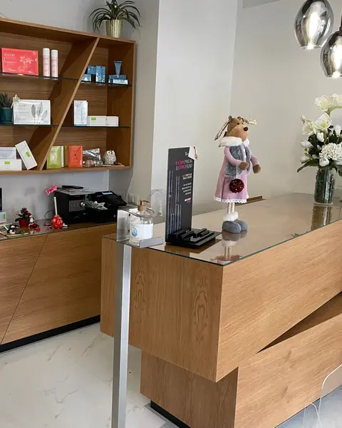 Un banco d’accoglienza in legno a blocchi sfalsati, con dietro una libreria a ripiani obliqui