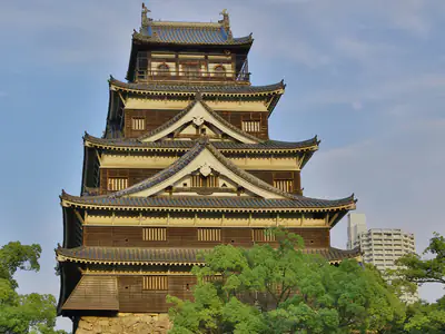 Il torrione nero e bianco del Castello di Hiroshima tra gli alberi