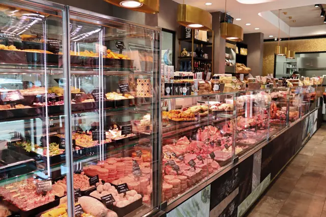 Il negozio: le vetrine del banco con carni, piatti pronti e salumi, sotto le lampade color rame