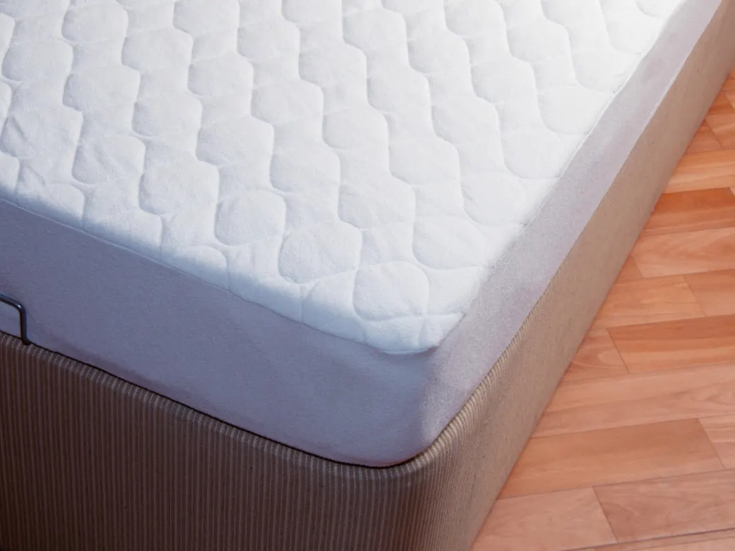 Un materasso trapuntato bianco su una rete, sul parquet