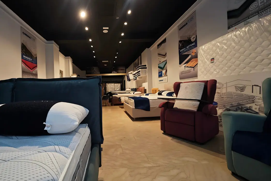 La sala del negozio: un letto con il cuscino bianco e nero, i materassi e le poltrone