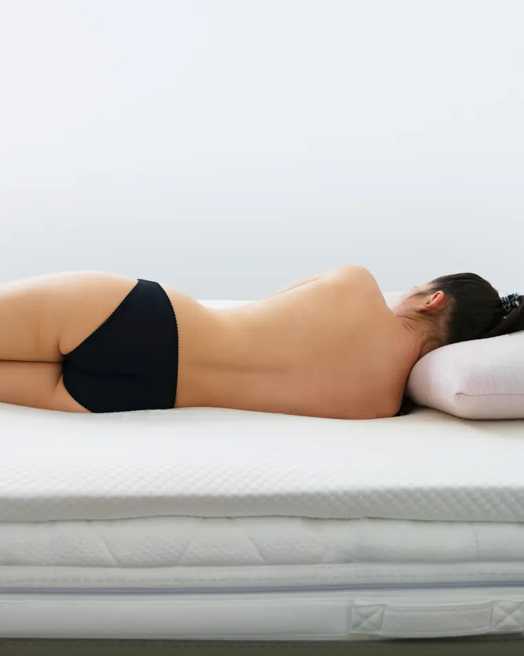 Una donna distesa a pancia in giù su un materasso bianco