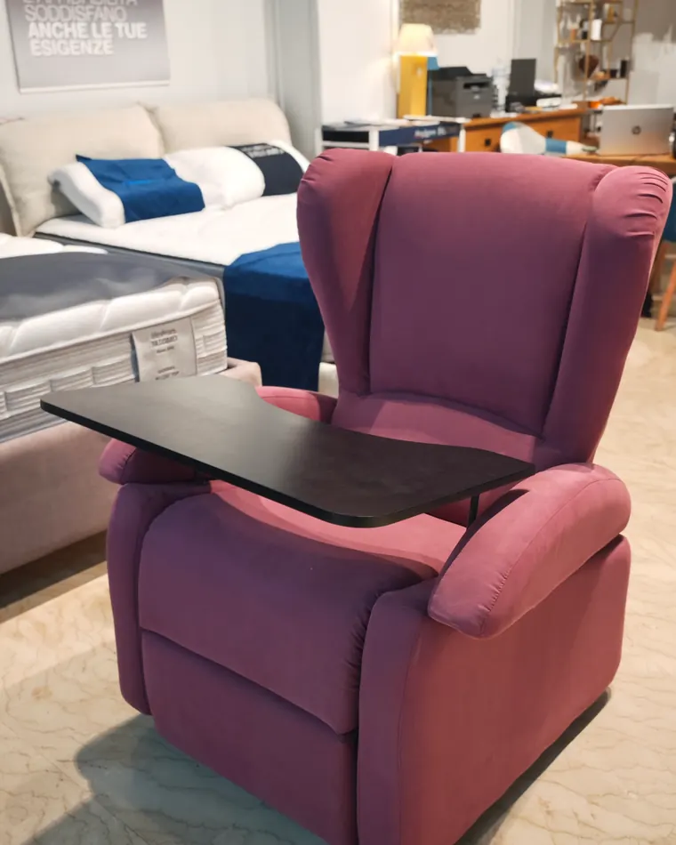 Poltrona relax rosa con il tavolino, tra i materassi esposti nel negozio