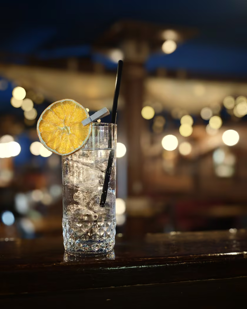 Cocktail trasparente con fetta di arancia sul bancone