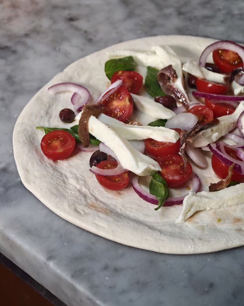Pizza con pomodorini, cipolla e mozzarella durante la preparazione