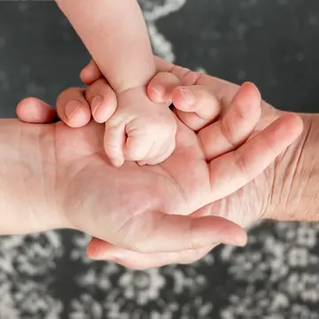 La mano di un bambino appoggiata sulle mani di due adulti