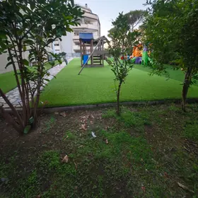 Il giardino tra gli alberi, con la struttura dei giochi in fondo