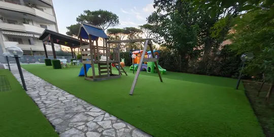 Il giardino con il vialetto di pietra, l'altalena e la casetta di legno