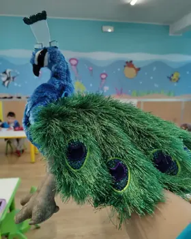 Un pavone di peluche in un'aula, davanti al mare dipinto sulla parete