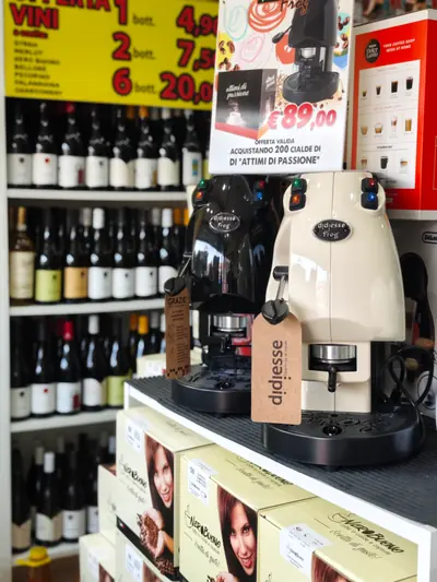 Il negozio: macchine da caffè e confezioni Nero Buono davanti allo scaffale dei vini