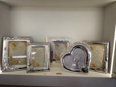 Cornici d’argento lavorate, fra cui una a cuore, su una mensola illuminata