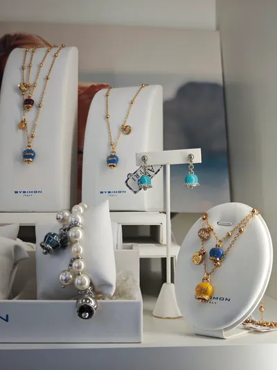 Collane e orecchini con le campanelle smaltate BySimon, accanto a un bracciale di perle
