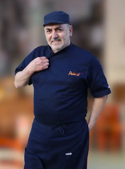 Pasquale, il maestro pizzaiolo, nella giacca da cuoco blu con il marchio di Paco Pì
