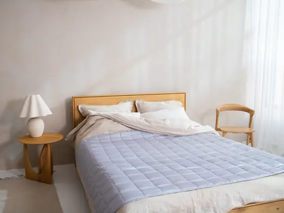 Camera da letto chiara, con un letto in legno e una trapunta azzurra