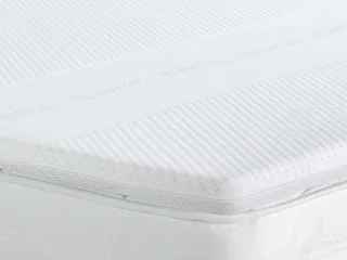 Topper bianco steso su un materasso, visto di taglio