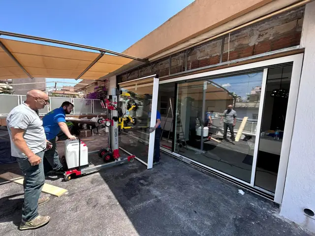 La squadra di Progetto Infissi monta una grande vetrata scorrevole su un terrazzo, con un sollevatore a ventose
