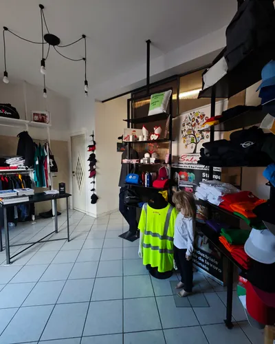 Lo showroom: scaffali neri con cappellini, felpe e giubbotti ad alta visibilità, e le lampadine appese al soffitto