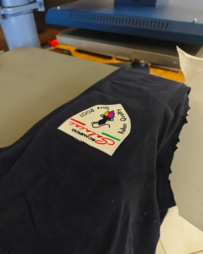 Una maglietta blu con lo stemma ricamato del Ricamificio Salvini, appena uscita dalla pressa