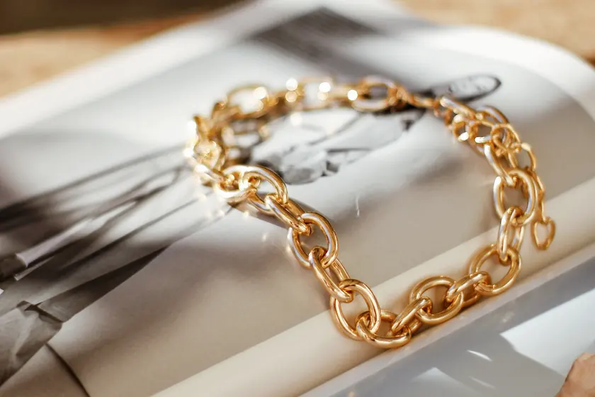 Bracciale a catena in oro giallo appoggiato su una rivista