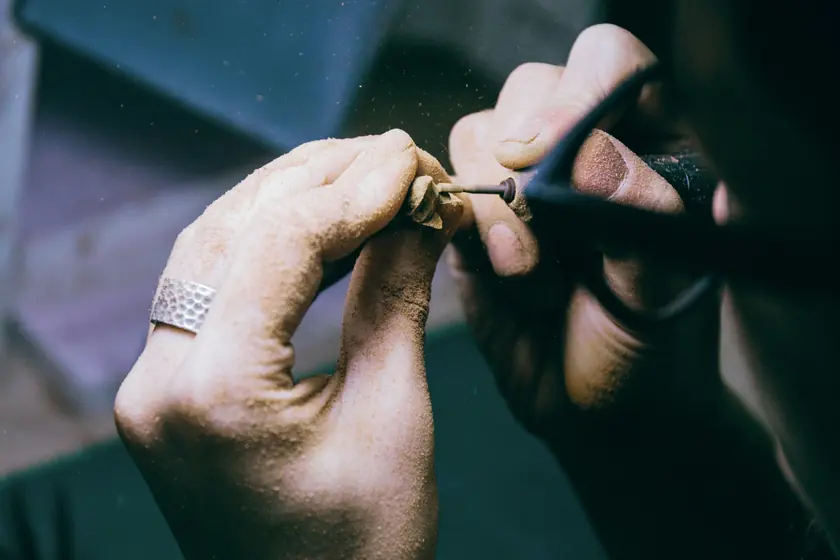 Le mani di un orafo che lavorano un anello con una piccola fresa